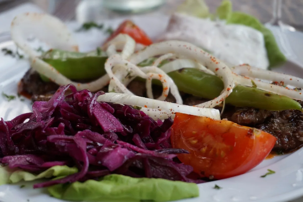 Lamm mit Rokrautsalat, gegrillter Paprika, Cacık und Evis Zwiebeln.