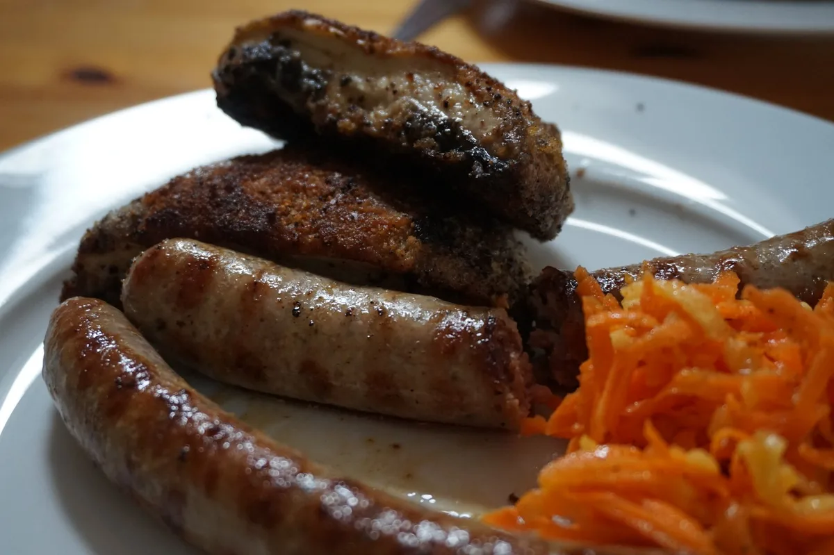 Panierte Rosellas mit Bratwurst und Gelbe-Rüben-Salat.