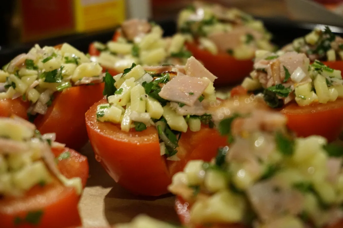 Die Tomatenhälften mit Käse, Schinken und Petersilie beschichtet.
