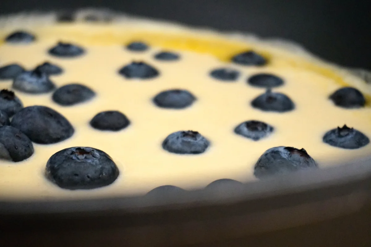 Die Blaubeeren im Pfannkuchenteig in der Pfanne.